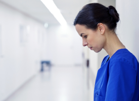 Female doctor standing in a hospital corridor with her head slightly dropped