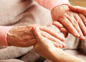 Young person holding the hands of an elderly person