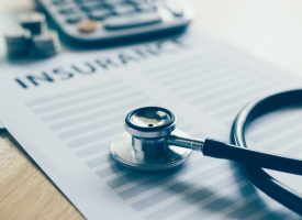 Insurance document, calculator and stethoscope 