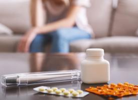 Image of woman in pain with prescription medicines on coffee table