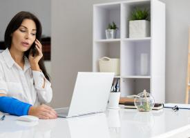 Office worker on phone with bandaged arm