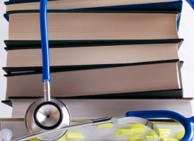 medical books with stethoscope draped over 