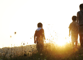 Children standing in a field at sunset. 