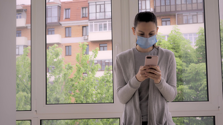Woman in blue face mask looking at mobile phone