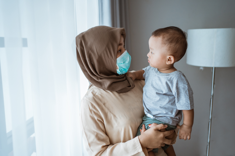 Woman in face mask holding toddler