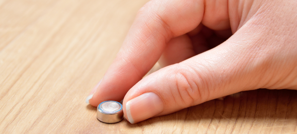 Hand holding a button battery