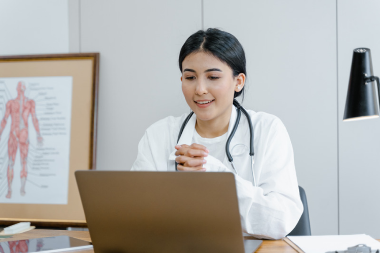 Female doctor in her consulting room talking to patient on lap top video