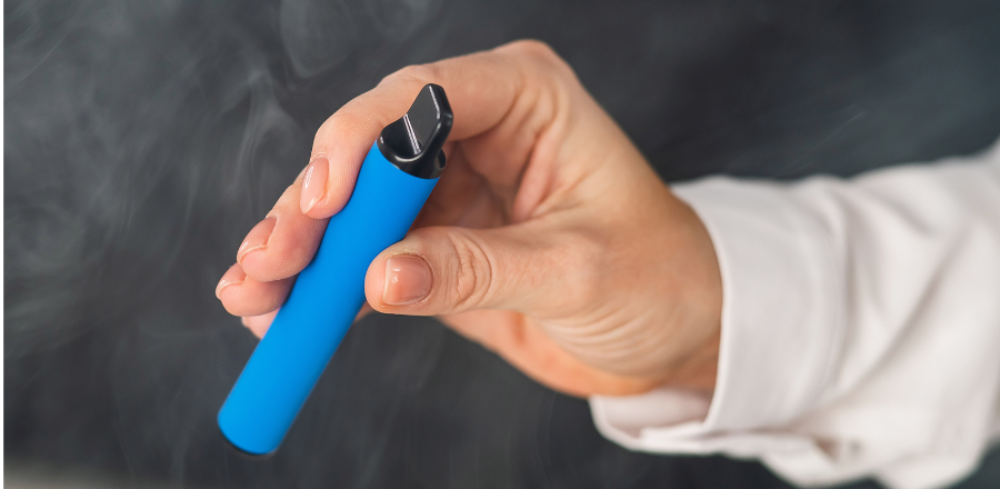 Woman's hand holding a blue disposable vape